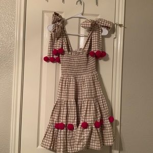 Neutral gingham sundress with ruching, hot pink pom poms, and tie straps!